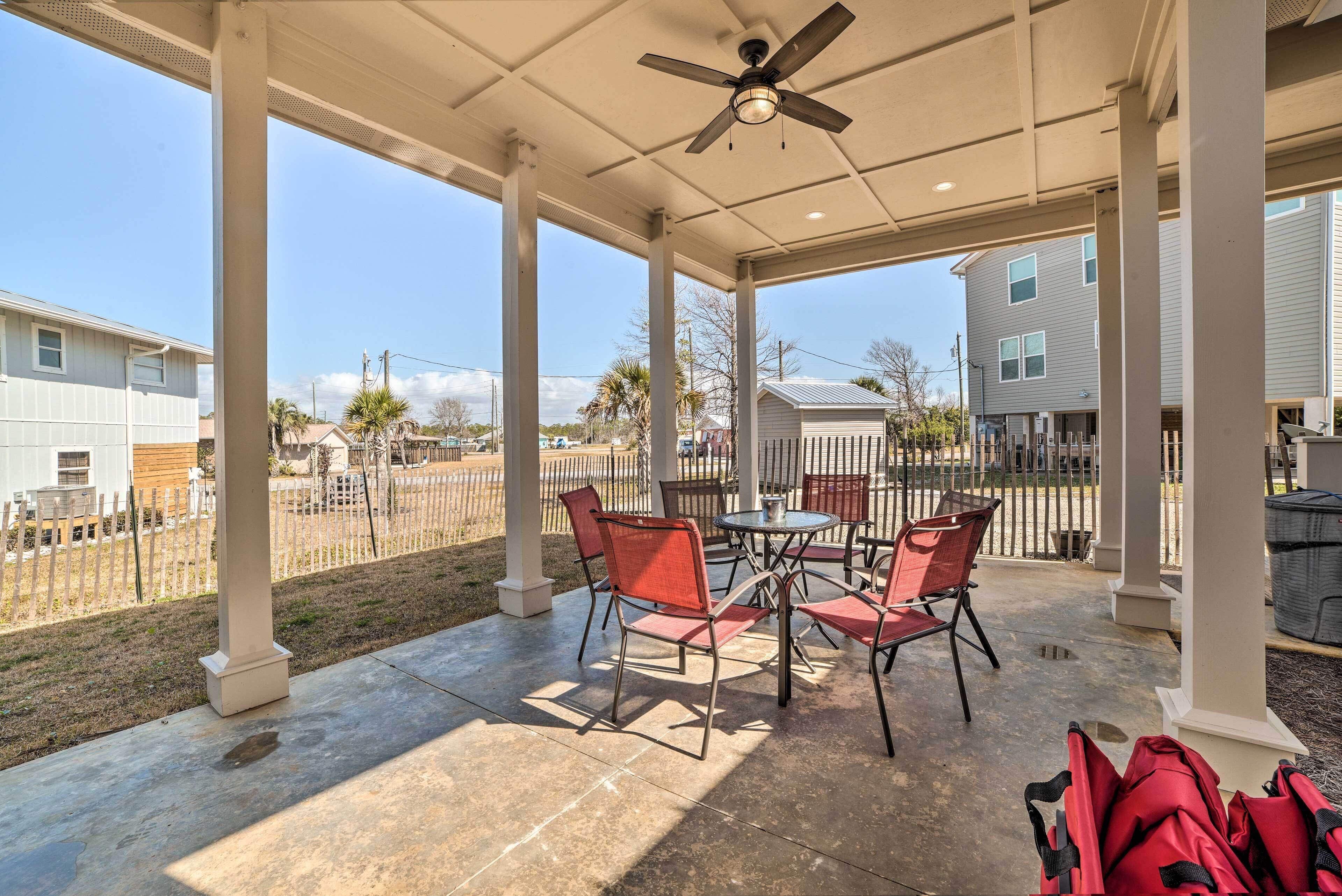 A covered patio area with a table and chairs, a ceiling fan, and a view of neighboring houses.