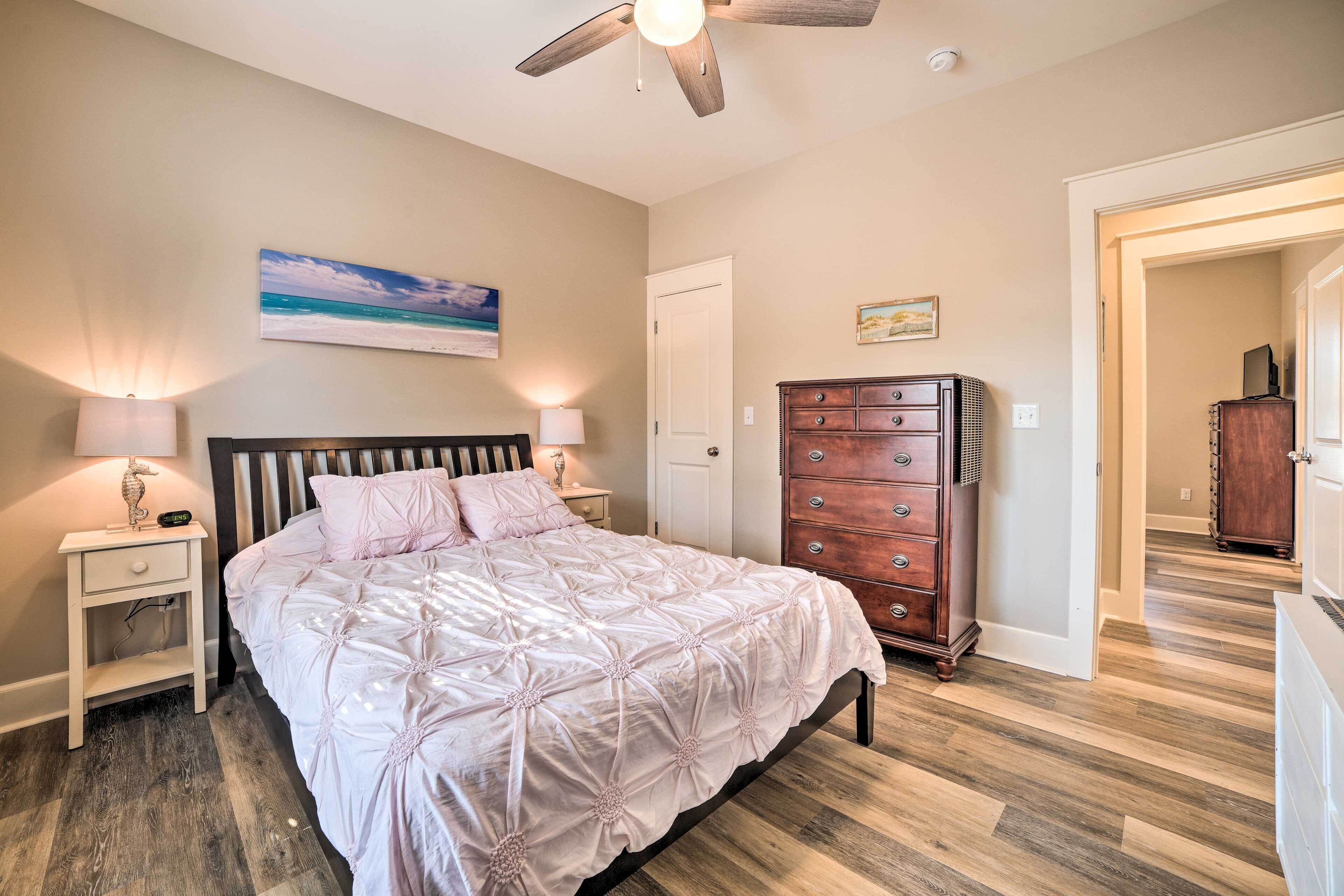 A bedroom with a bed, nightstands, a dresser, and a ceiling fan.