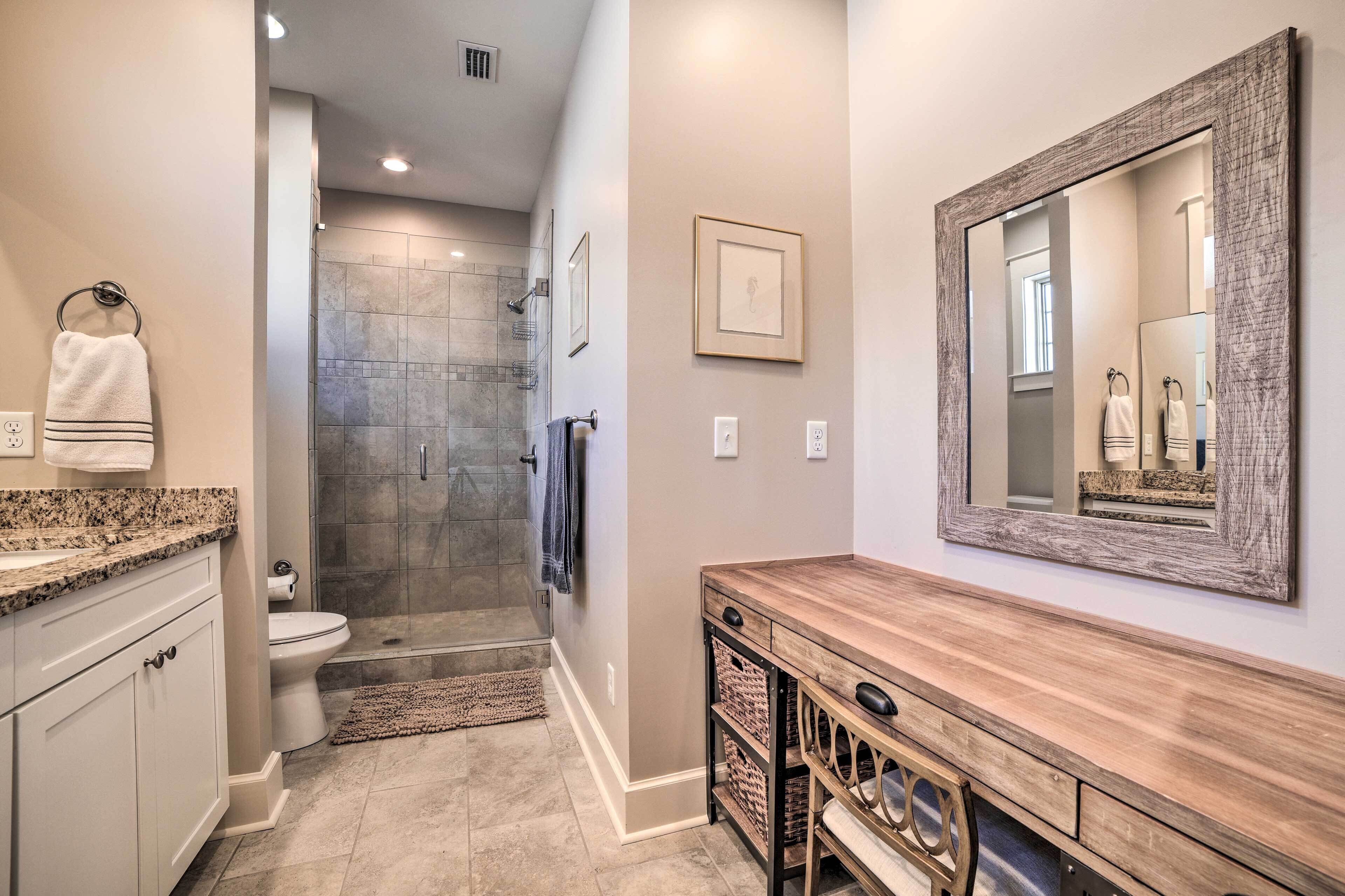 A modern bathroom with a shower, toilet, vanity, and a large mirror.