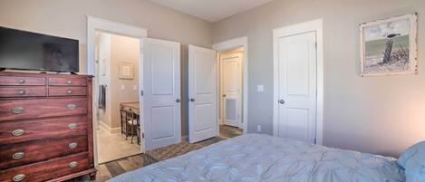 A bedroom with a bed, dresser, television, and ceiling fan.
