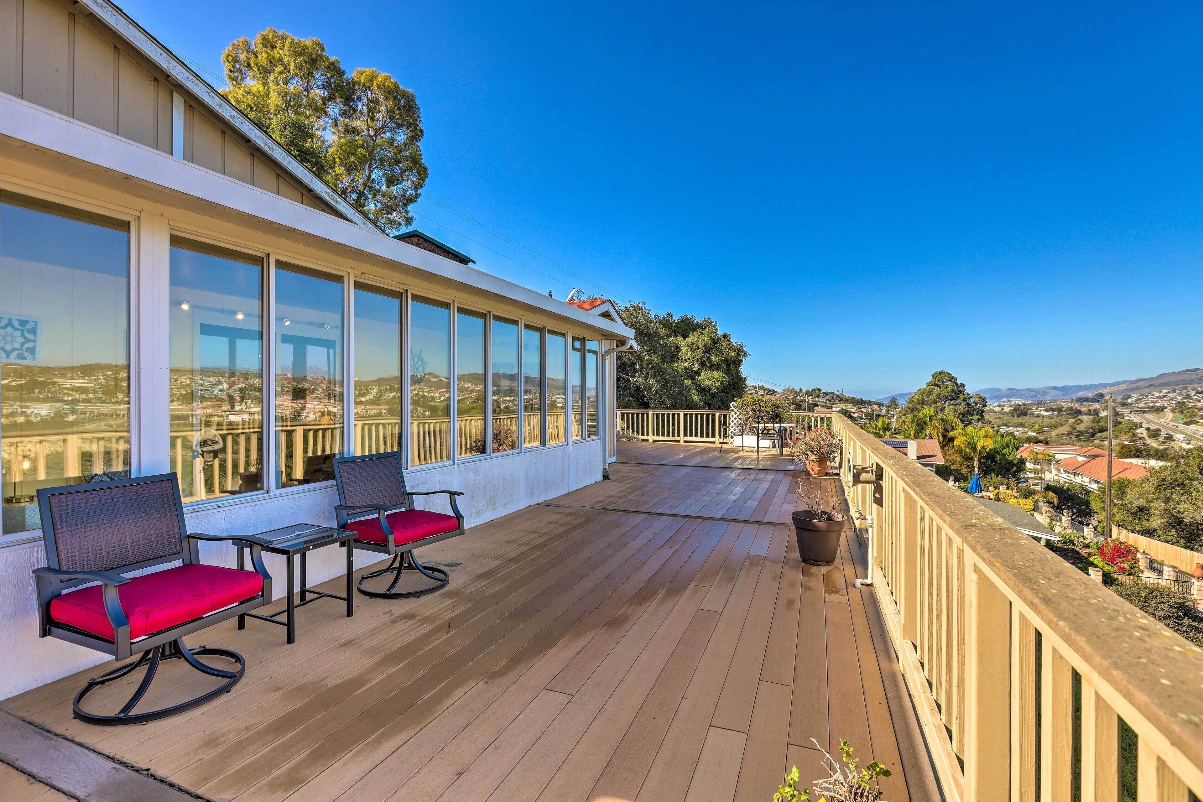 A wooden deck with two chairs and a table, overlooking a scenic landscape.