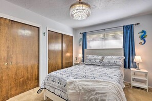 Een slaapkamer met een bed, twee nachtkastjes, een kroonluchter, een kledingkast en een raam met gordijnen.