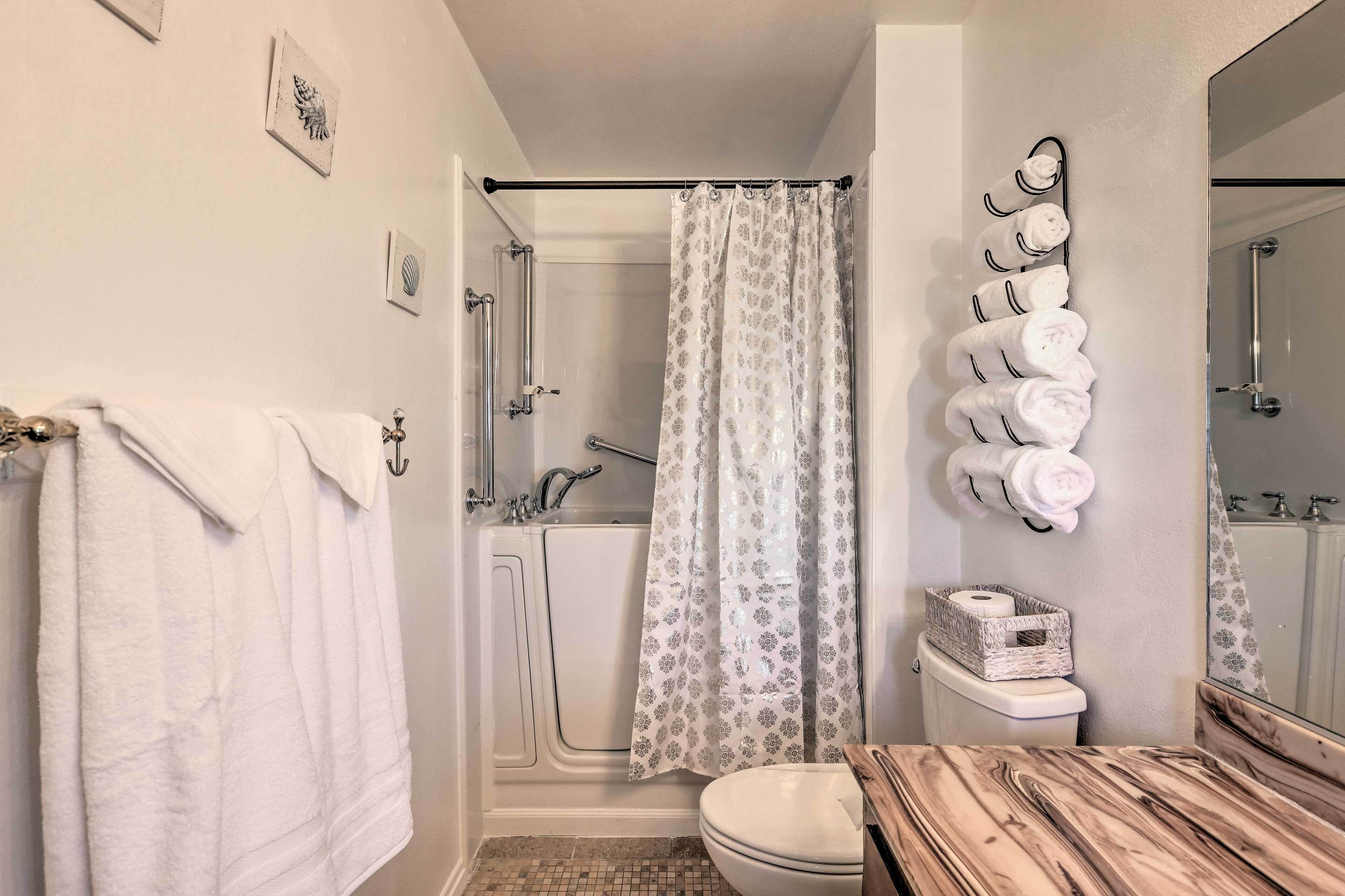 Een badkamer met een douche, toilet en een houten wastafelmeubel.