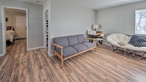 A modern living room with a grey sofa, a wicker chair, and a small table with a lamp. - Authentic Escape at the Exact Center of CA! (North Fork)