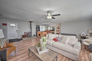 Un salon avec un canapé, une table basse et un ventilateur de plafond. On y trouve une porte avec un panneau indiquant «Interdiction de fumer», un piano et une bibliothèque.