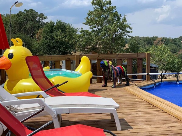 A poolside area with lounge chairs, a large inflatable duck float, and a small pool.
