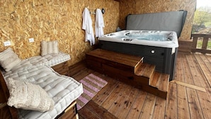 Una terraza de madera con un jacuzzi, un sofá y un banco.