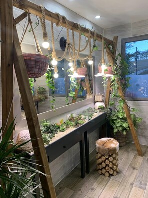 A modern kitchen with a wooden trellis, hanging lights, and a variety of plants.
