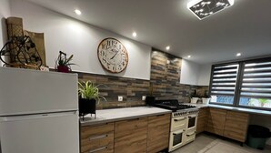 Una cocina moderna con un reloj grande, armarios de madera, una estufa y un refrigerador.