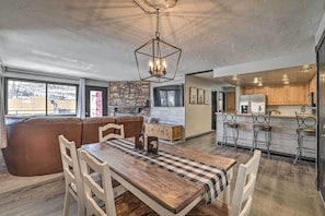 A modern kitchen with wooden cabinets, a stainless steel refrigerator, and a bar area with stools.