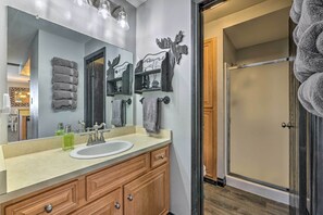 A bathroom with a large mirror, wooden vanity, and a glass shower enclosure.