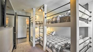 Een kamer met stapelbedden, een spiegel en een gang die naar een keuken leidt.