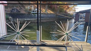 A wooden dock with a view of a calm river and a small bridge in the background.