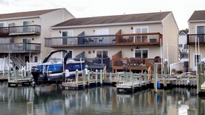 Un edificio residencial frente al agua con balcones, un muelle y un barco.