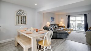 Una sala de estar moderna con una mesa de comedor, un sofá y un amplio ventanal con cortinas.