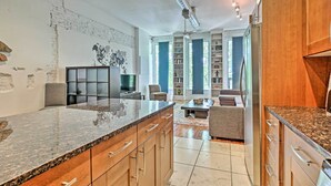 A modern kitchen with granite countertops, wooden cabinets, and a built-in bookshelf. - Walk to Dtwn Distilleries: Nulu Art District Loft (Louisville)