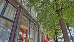 A row of historic buildings with large windows and a 'For Sale' sign. - Walk to Dtwn Distilleries: Nulu Art District Loft (Louisville)