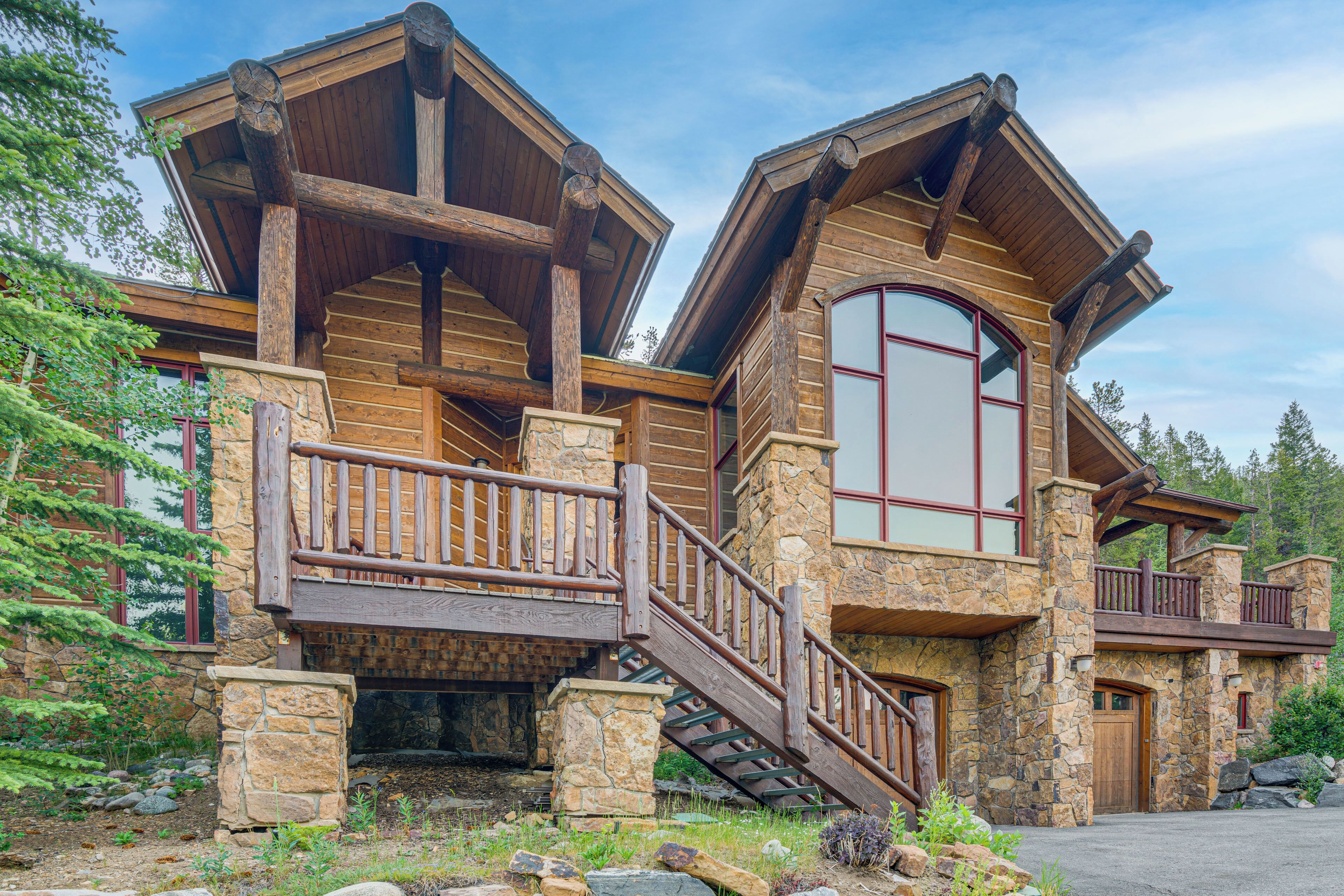A log cabin with a stone foundation, wooden balconies, and a stone staircase.