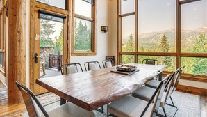 Ein Holzespeisesaal mit Stühlen, große Fenster mit Blick auf die Berge und ein Steinkamin.