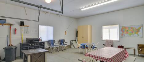 A spacious room with a kitchenette, a dining table with chairs, a map on the wall, and a window with blinds.