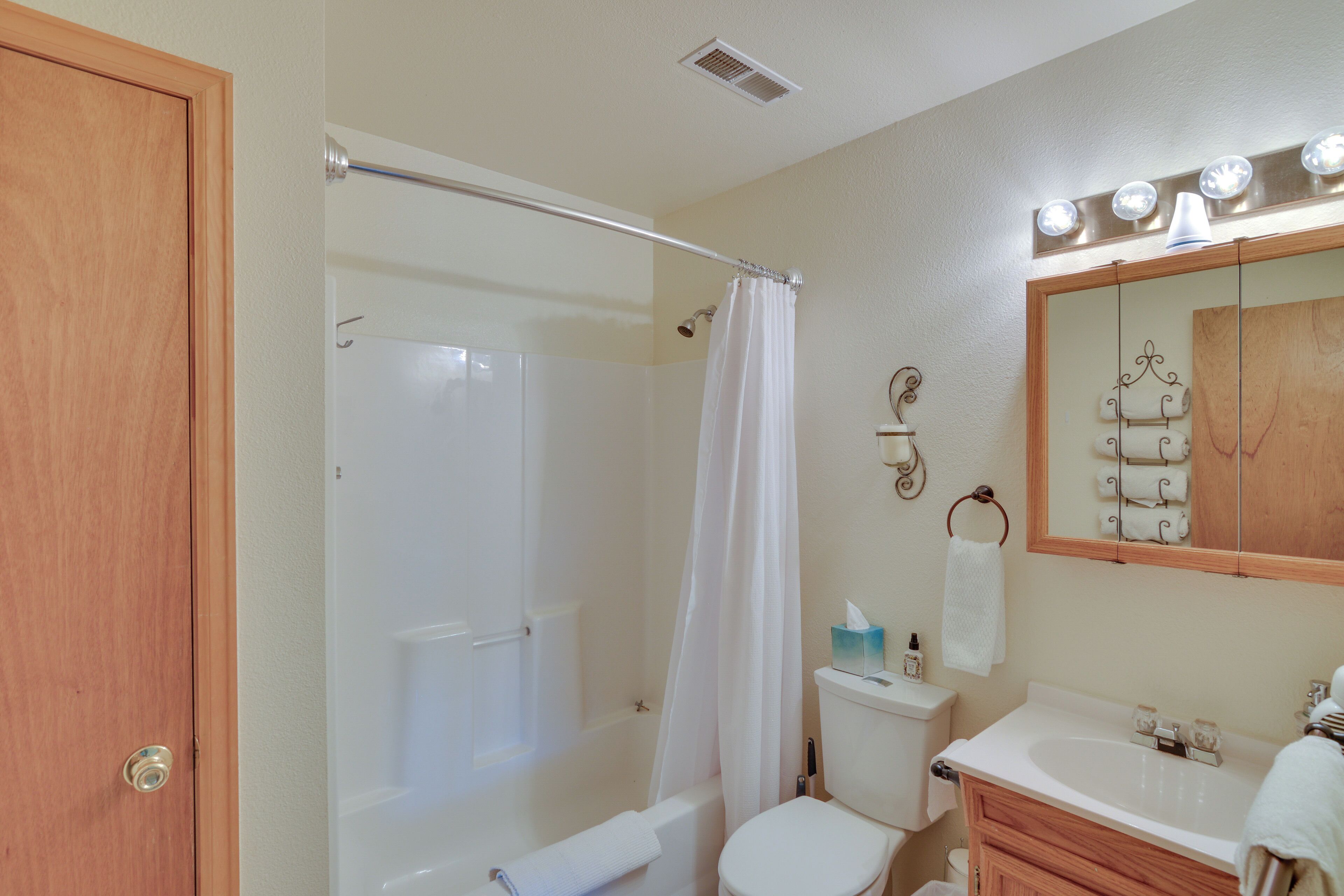 A bathroom with a shower, toilet, sink, and vanity.