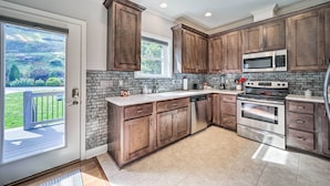 A kitchen with dark wooden cabinets, a stainless steel microwave, and an oven. - Striking Waynesville Home w/ Mtn Views & Deck (Waynesville)