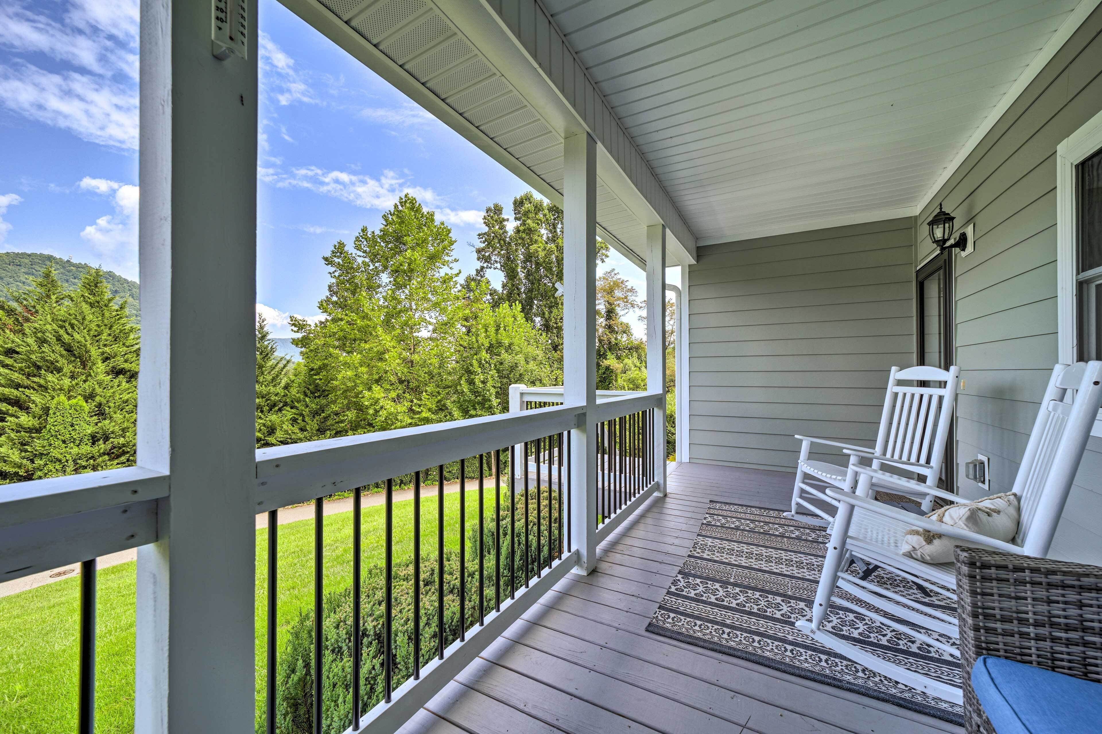 A covered porch with white railings, a wicker chair, and a bench.