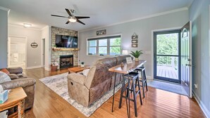 A spacious living room with a fireplace, leather sofa, and a dining area with a bar stool. - Striking Waynesville Home w/ Mtn Views & Deck (Waynesville)