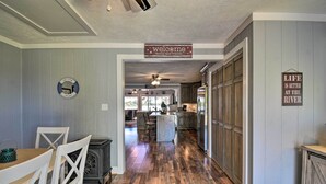 A spacious kitchen with wooden flooring, a dining area with white chairs, and a central island. - Riverfront Cottage: Fire Pit & Kayaks (Deltaville)