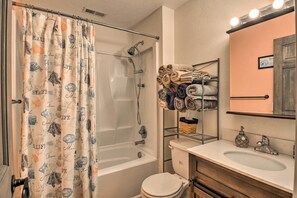 A bathroom with a bathtub, shower, toilet, and a sink with a mirror above it. - Riverfront Cottage: Fire Pit & Kayaks (Deltaville)