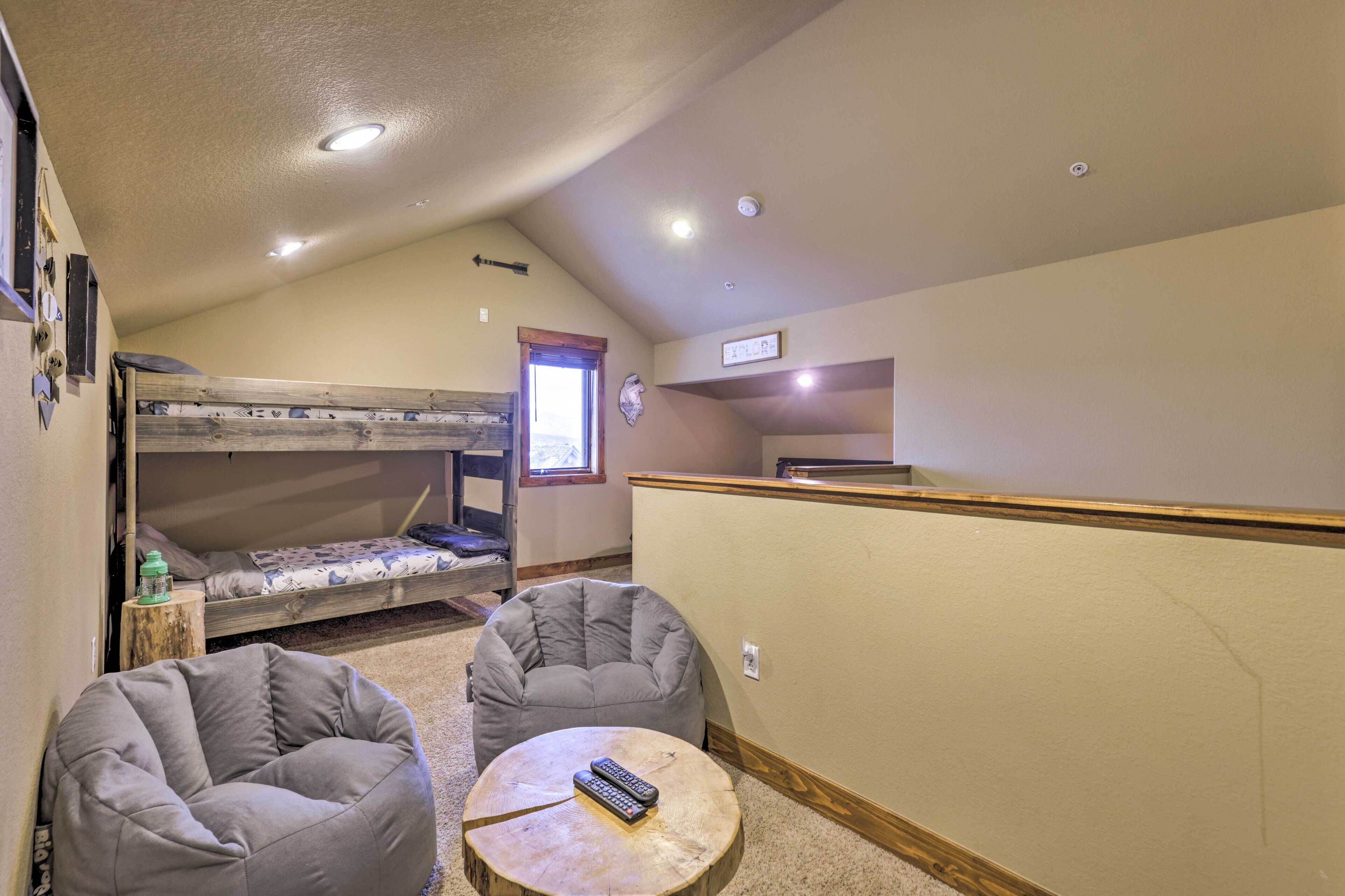 Una cama litera, dos sillones de mimbre, una mesita redonda con un control remoto y una ventana con vistas al exterior.