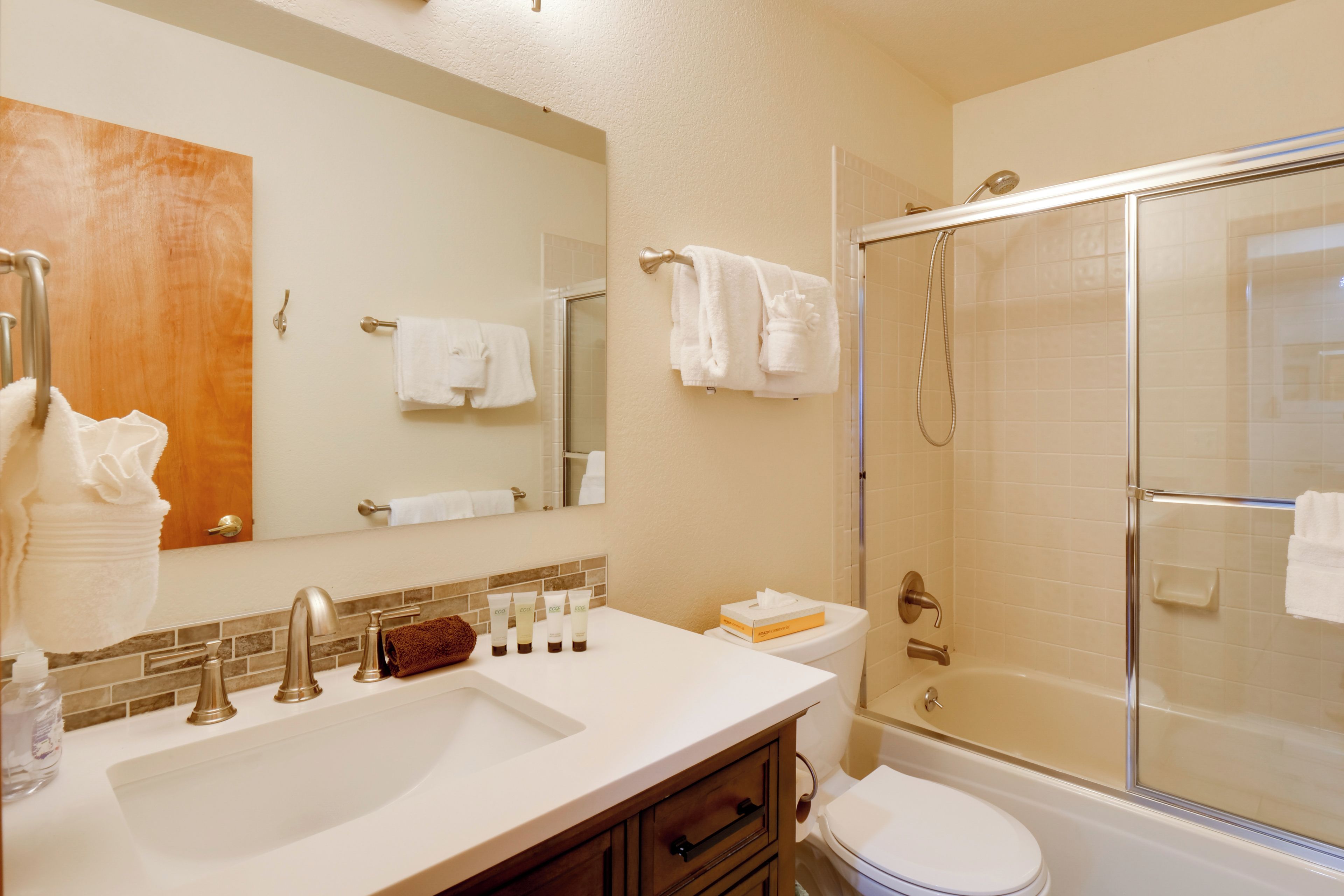 A bathroom with a sink, mirror, towel rack, and a glass-enclosed shower.