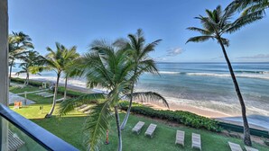 A balcony with a view of the ocean, palm trees, and lounge chairs. - Whale & Sunset Views: Oceanfront Lahaina Condo (Kaanapali)
