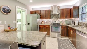 Eine moderne Küche mit Granit Arbeitsplatten, Edelstahlgeräten und Holzschränken.