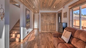 A spacious room with a wooden ceiling, a brown leather sofa, and a large wooden door. - Fairplay Cabin w/ Pool Table, Deck & Mountain View (Fairplay)