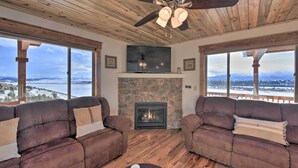 A cozy living room with two leather sofas, a stone fireplace, and a large TV. - Fairplay Cabin w/ Pool Table, Deck & Mountain View (Fairplay)