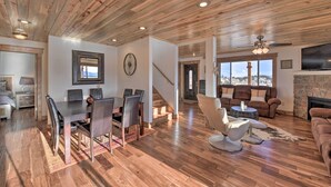 A spacious living area with a wooden ceiling, a dining area with a table and chairs, a fireplace, and a large window offering a view. - Fairplay Cabin w/ Pool Table, Deck & Mountain View (Fairplay)
