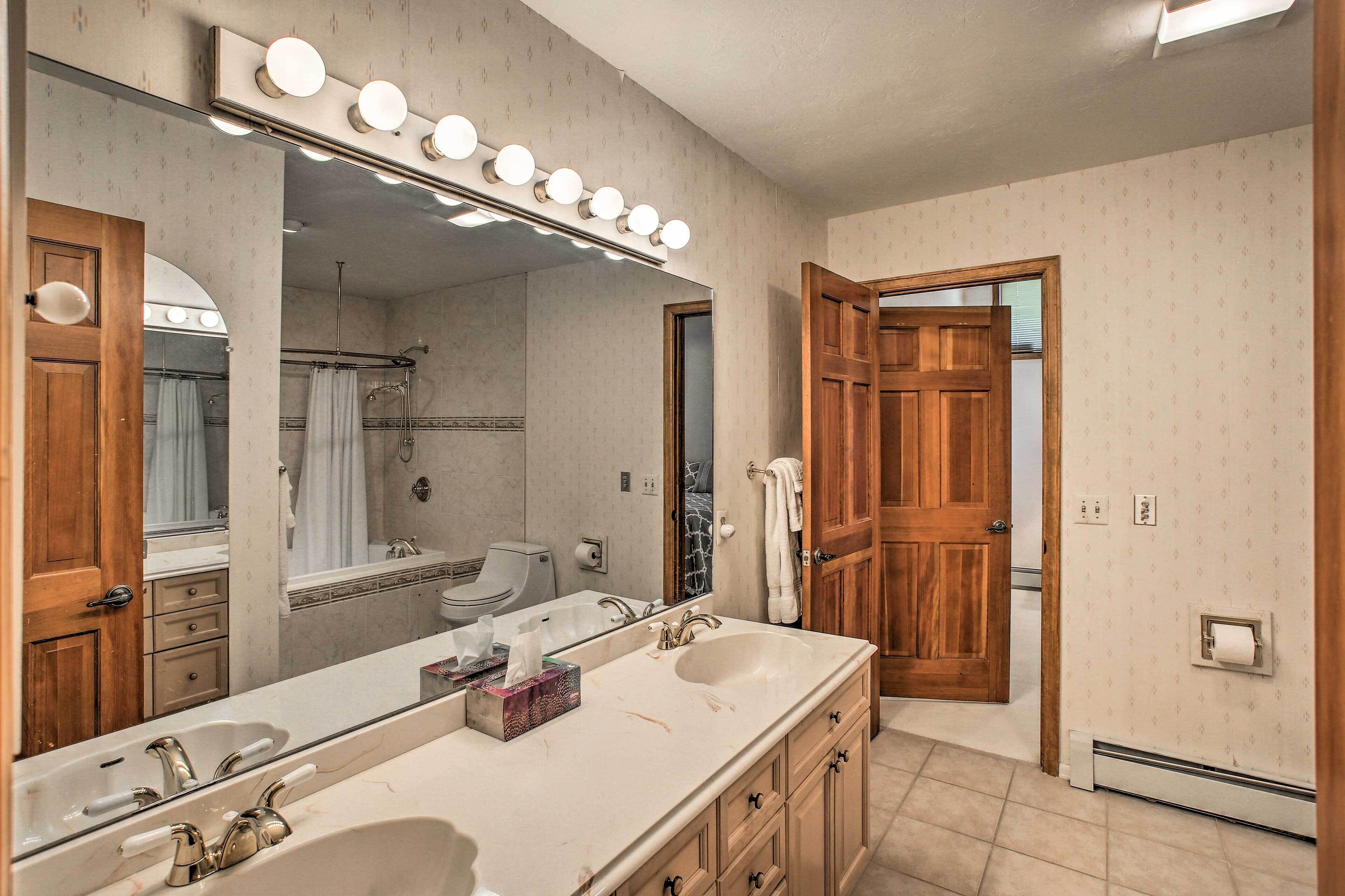 A bathroom with a large mirror, vanity with dual sinks, and a shower area.