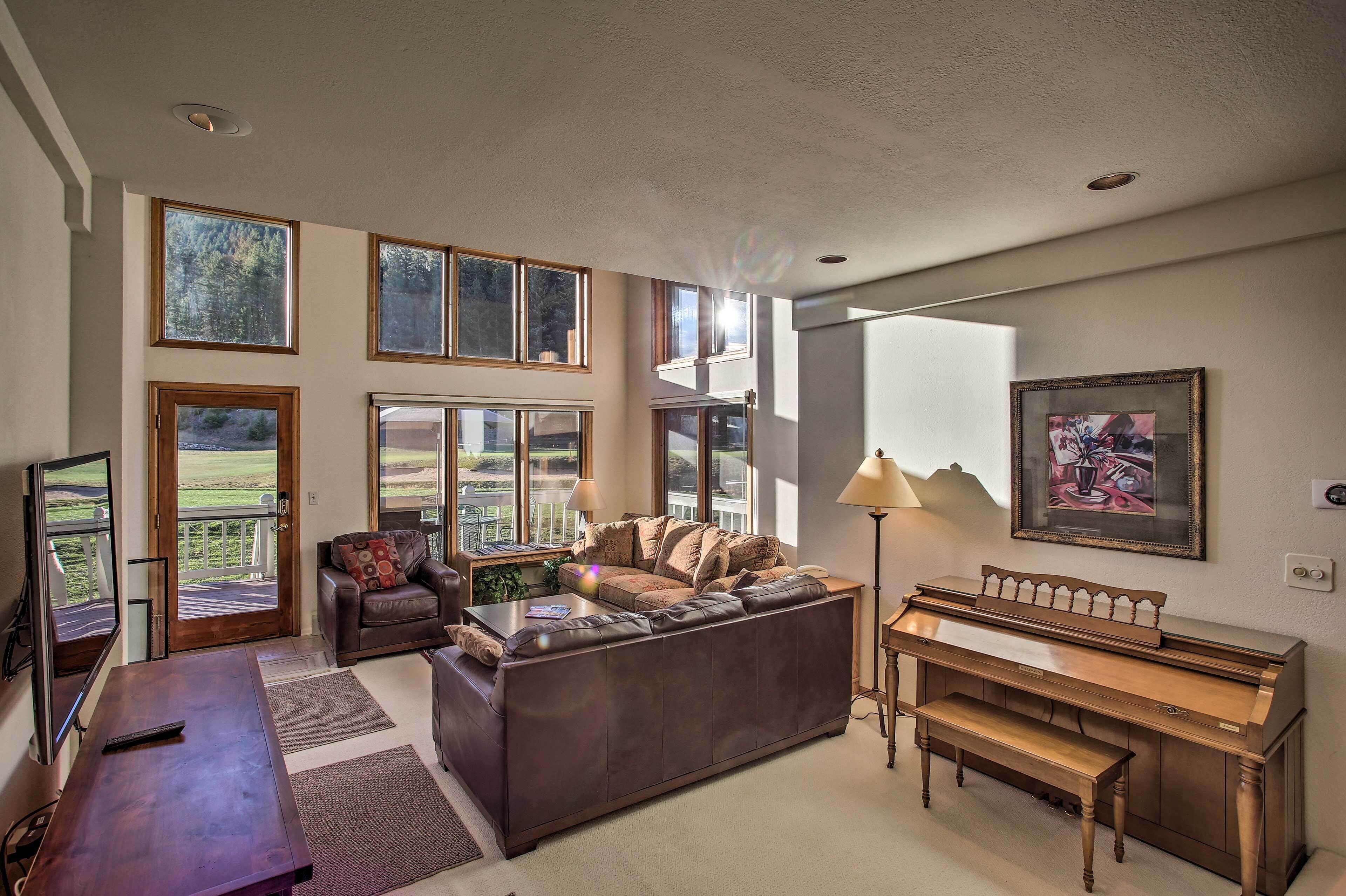 A spacious living room with a large sectional sofa, a piano, and a television.