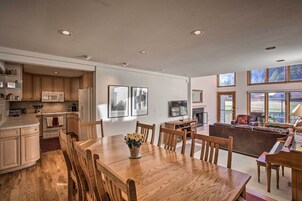 Cozinha moderna com armários de madeira, uma mesa de jantar e um piano na sala de estar.
