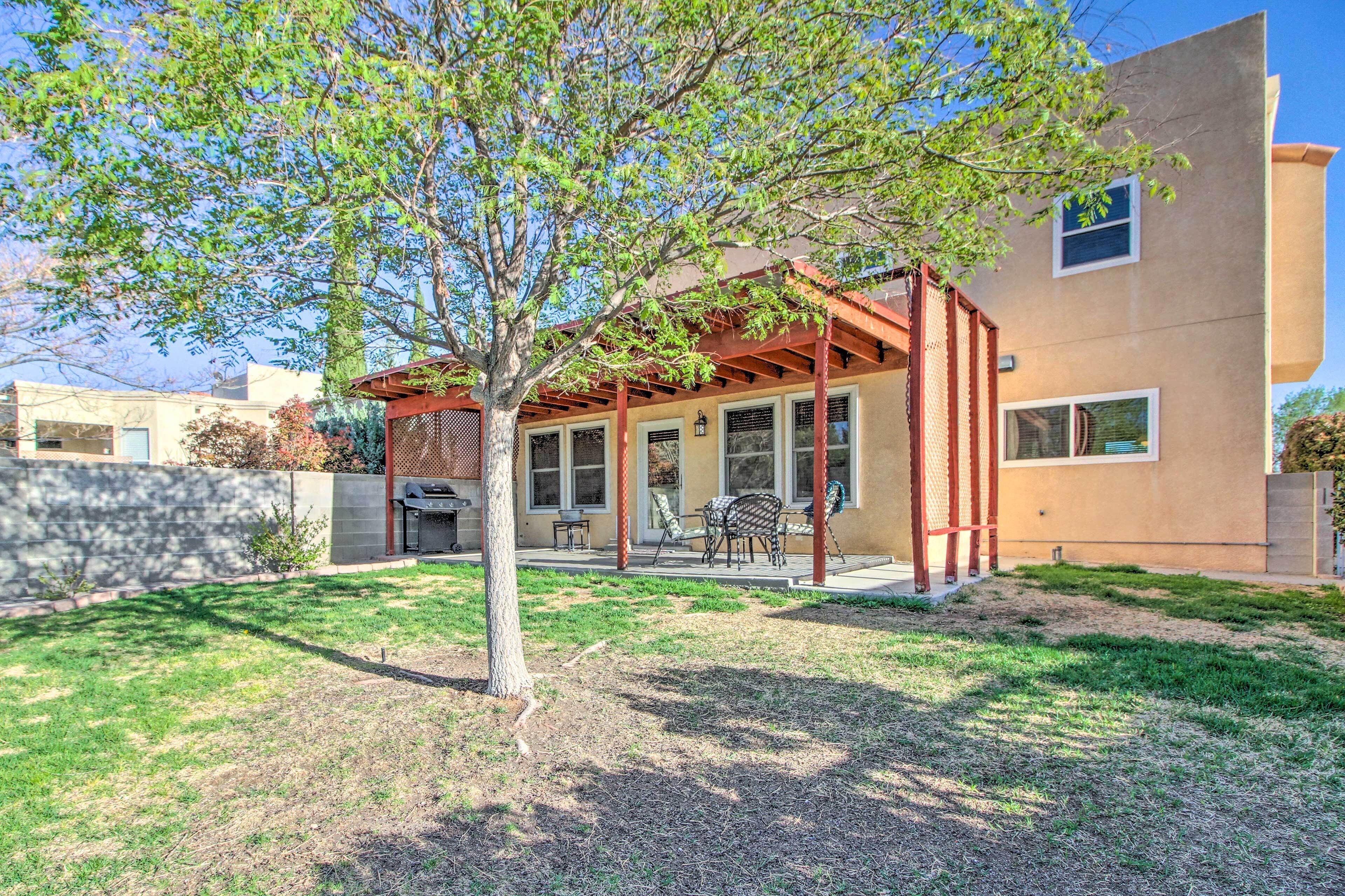 A modern house with a patio, a tree, and a clear sky.