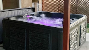 Un jacuzzi con revestimiento de piedra, estructura de madera y luz púrpura.