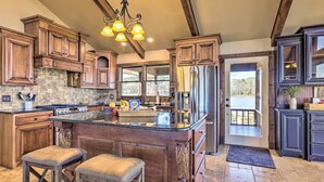A spacious kitchen with a large island, wooden cabinets, and a view to the outside. - Lay Lake Access & Views: Expansive Shelby Home! (Shelby)
