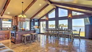 A spacious kitchen with a large island, wooden bar, and dining area with a view of the water. - Lay Lake Access & Views: Expansive Shelby Home! (Shelby)