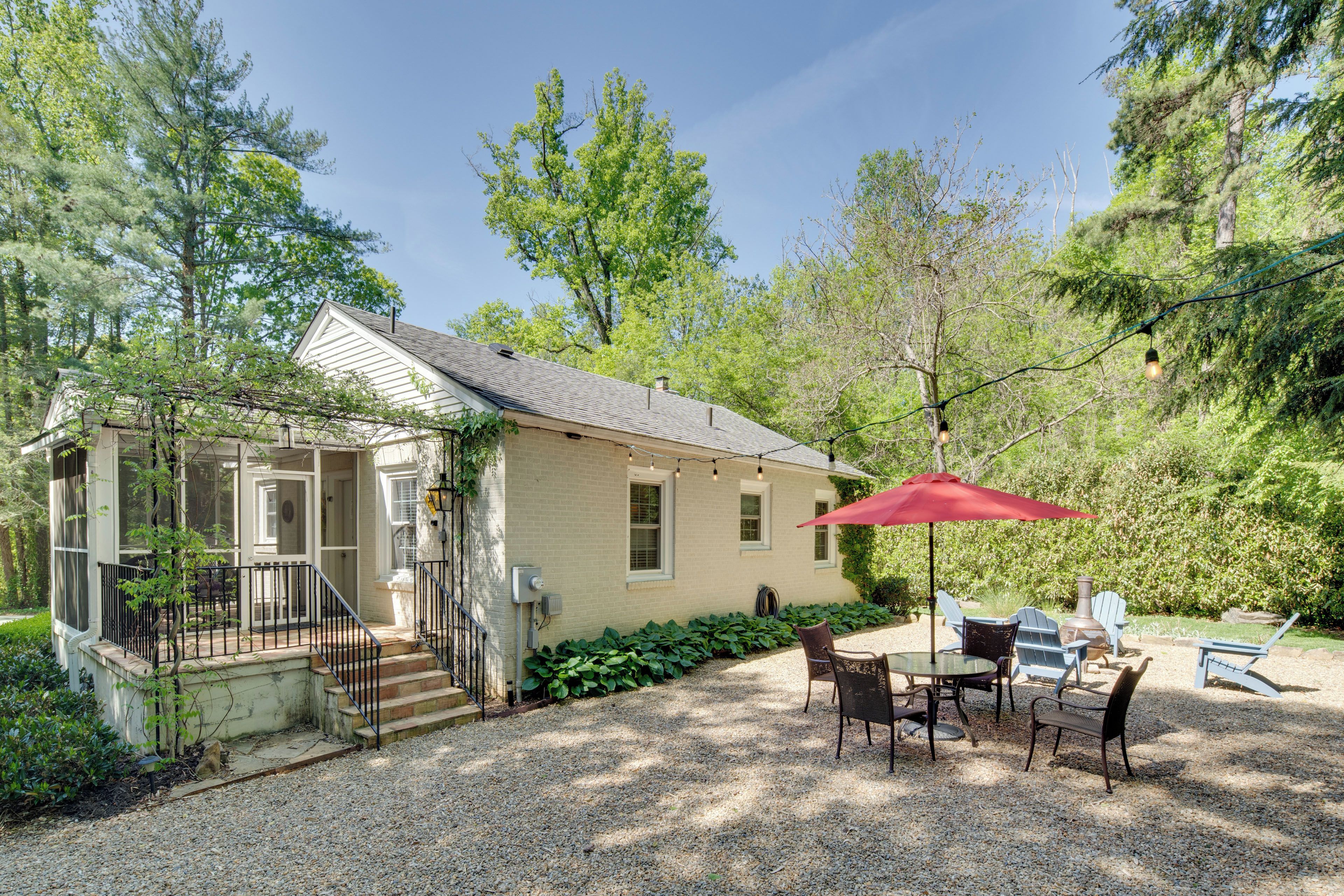 A house with a covered patio, outdoor seating, and a gravel driveway.