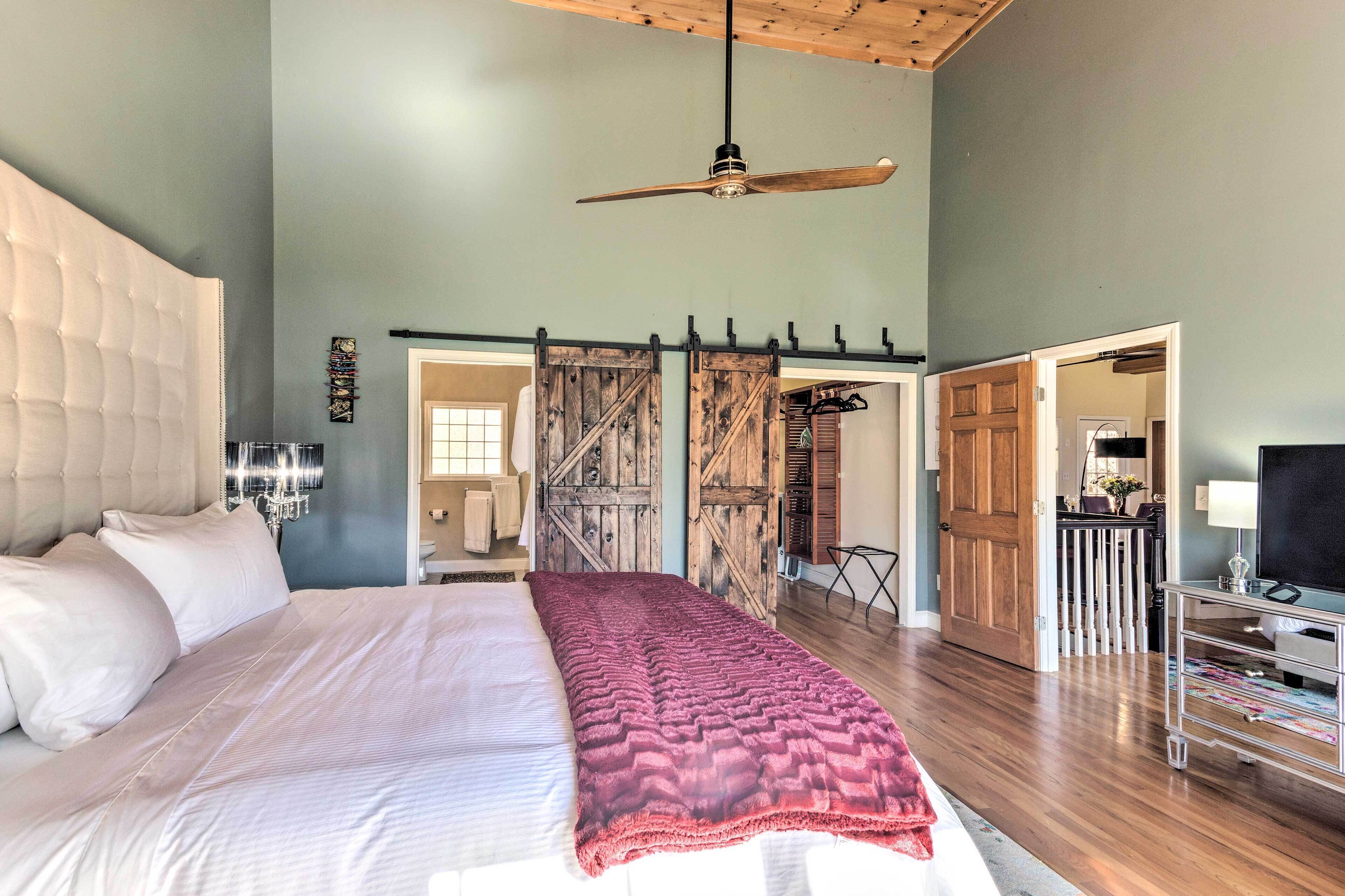 A spacious bedroom with a large bed, a ceiling fan, and a view of the outside through a sliding door.