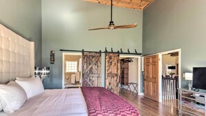 A spacious bedroom with a large bed, a ceiling fan, and a view of the outside through a sliding door. - Asheville Retreat w/ Game Room & Mountain Views! (Asheville)