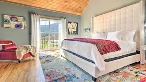 A bedroom with a large bed, a red sofa, a wooden ceiling, and a view of the outdoors. - Asheville Retreat w/ Game Room & Mountain Views! (Asheville)