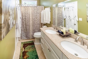 A bathroom with a double sink, a toilet, a shower with leopard print curtains, and a large mirror. - Asheville Retreat w/ Game Room & Mountain Views! (Asheville)