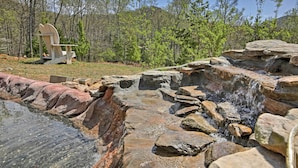 A natural setting with a wooden chair, a small waterfall, and a forested area. - 11 Mi to Dtwn: Murphy Gem w/ Hot Tub & Mtn Views! (Murphy)